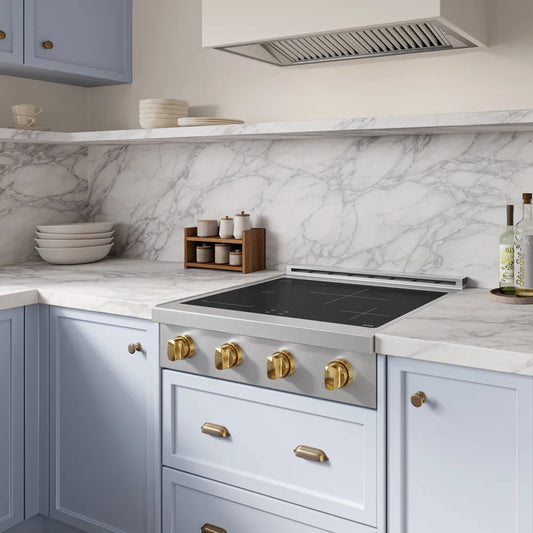Modern kitchen with marble backsplash, ZLINE Autograph Edition 30 in. Paramount Induction Rangetop with 4 Element Cooktop in Stainless Steel and Polished Gold Accents (SINRTZ-30-G), and light blue cabinets.