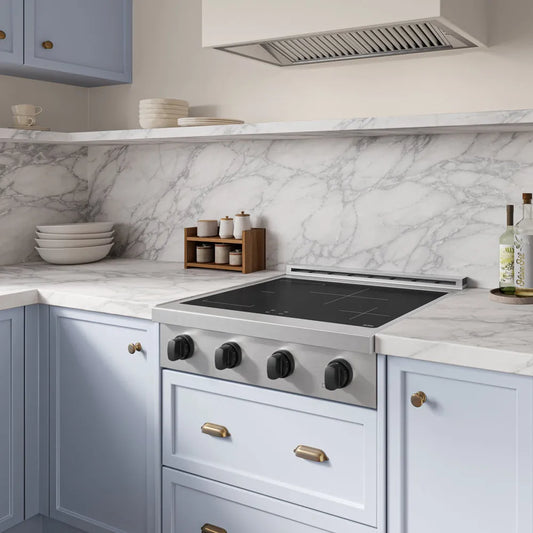 AZLINE Autograph Edition 30 in. Paramount Induction Rangetop with 4 Element Cooktop in Stainless Steel and Matte Black Accents (SINRTZ-30-MB), set into a light blue kitchen cabinet with a white marble backsplash and matching marble countertop.