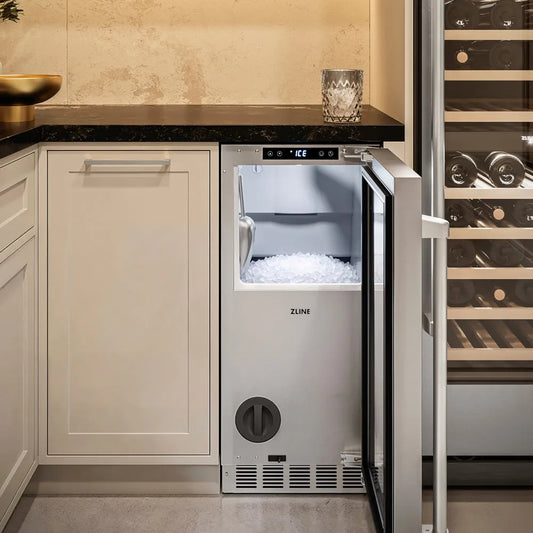 A ZLINE 15 in. Touchstone Nugget Ice Maker with Drain Pump and Solid Stainless Steel Door (INGD-ST-15), with its door open, showing nugget ice inside, set into a kitchen cabinetry unit next to a wine rack.