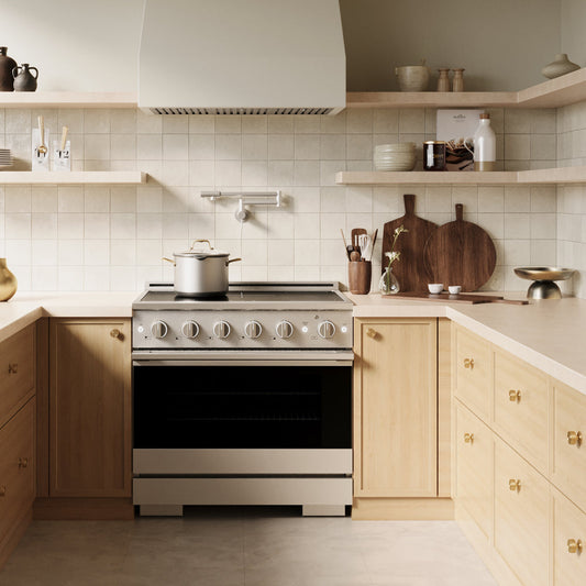 A ZLINE 36 in. 5.2 cu. ft. Marino Induction Range with 5 Element Cooktop and Electric Convection Oven in Stainless Steel (MINR36) installed in a modern kitchen with light wood cabinets, beige countertops, and a tiled backsplash.