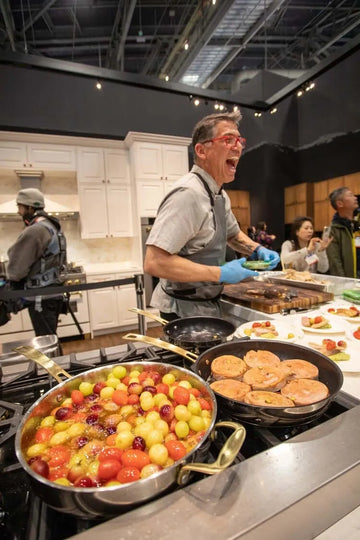 Chef cooking colorful grapes and seared meat on a ZLINE professional gas range at the KBIS 2024 trade show.