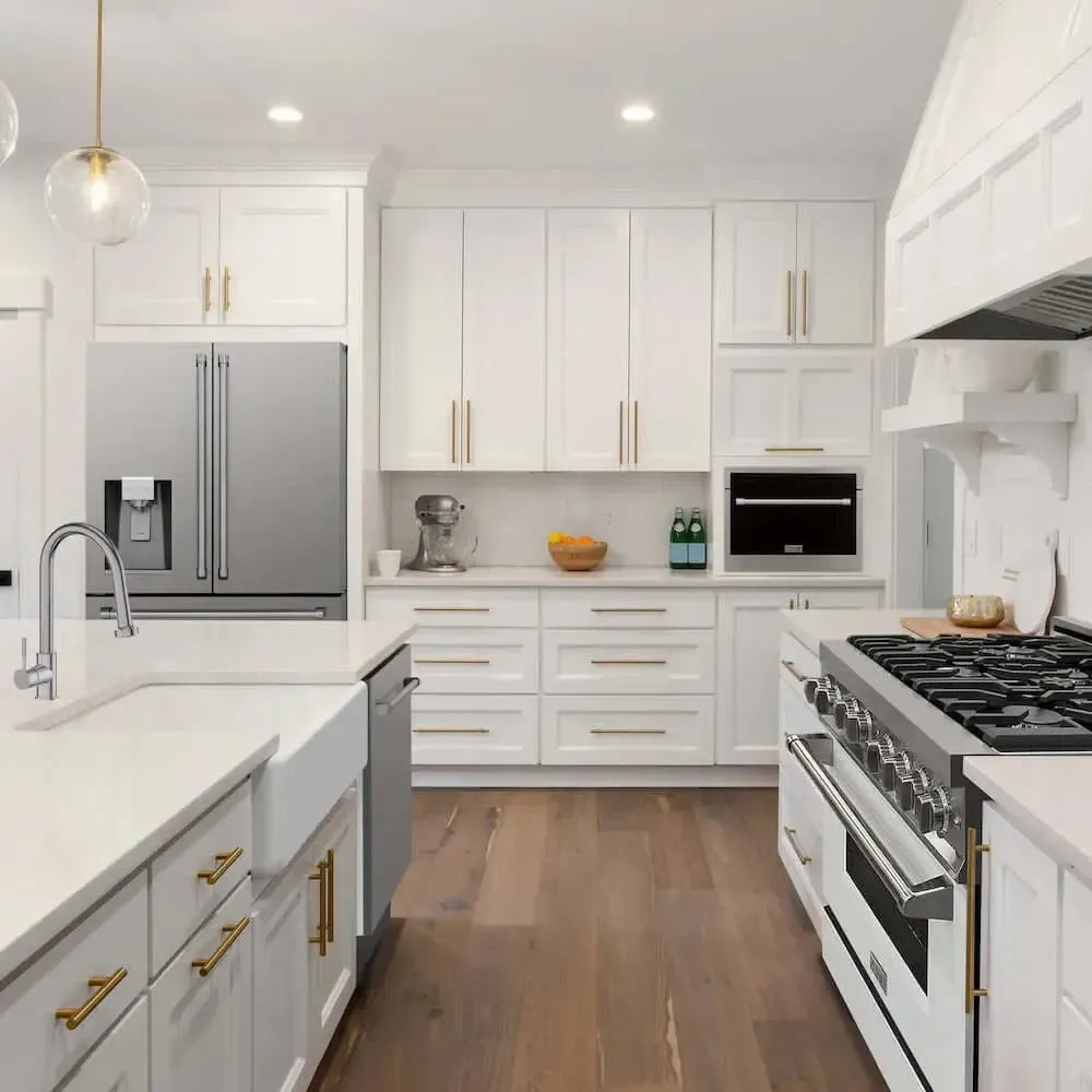 Stainless steel ZLINE refrigerator with water dispenser in a bright white kitchen with gold hardware.