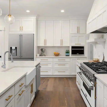 Stainless steel ZLINE refrigerator with water dispenser in a bright white kitchen with gold hardware.