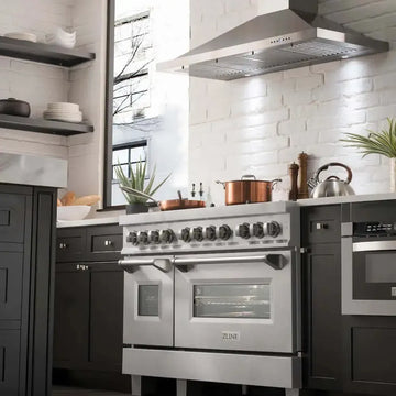 ZLINE satin stainless steel range and matching vent hood in a modern kitchen with dark cabinets and white brick.