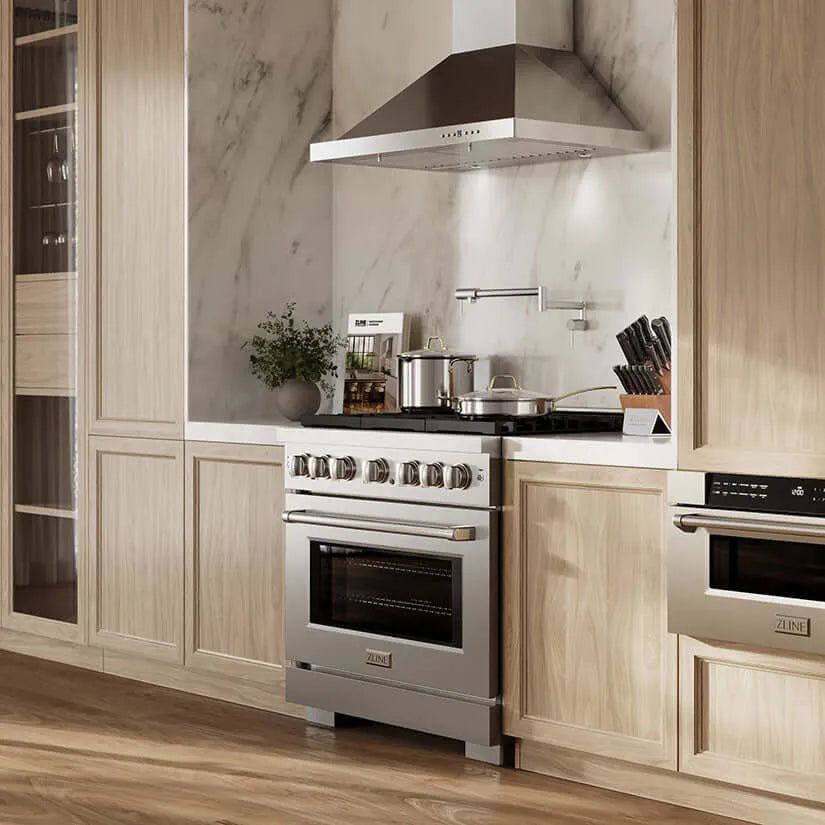 Stainless steel ZLINE gas range with professional hood in a modern kitchen with light wood cabinets and marble backsplash.