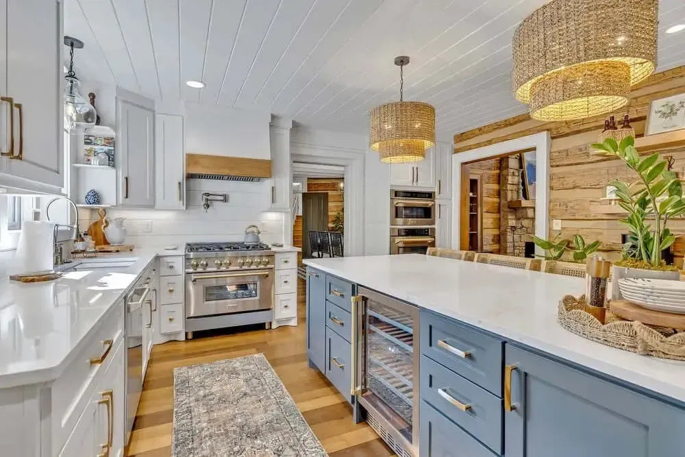 Modern kitchen in Columbia, TN featuring a blue island, white cabinets, gold hardware, and rustic wood accents.