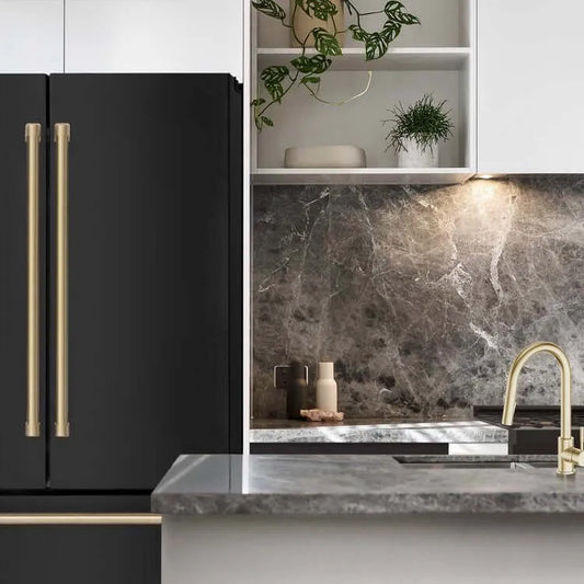 Matte black ZLINE refrigerator with gold handles next to a marble countertop and gold kitchen faucet.