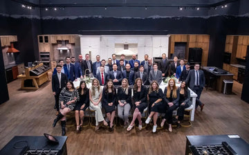 The ZLINE team posing in a modern kitchen showroom display at the 2023 KBIS trade show.