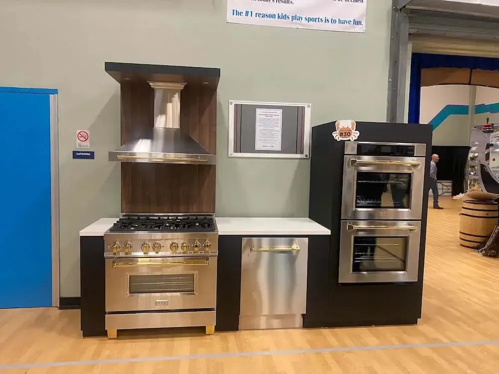 ZLINE stainless steel kitchen appliances with gold accents displayed at a Boys and Girls Club fundraiser event.