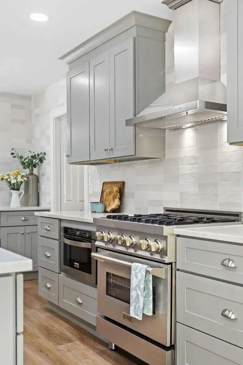 Modern kitchen with gray shaker cabinets, stainless steel range, and light gray subway tile backsplash.