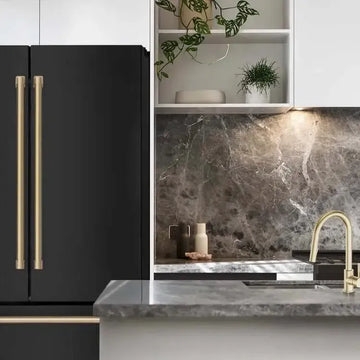 Matte black ZLINE refrigerator with gold handles next to a marble countertop and gold kitchen faucet.