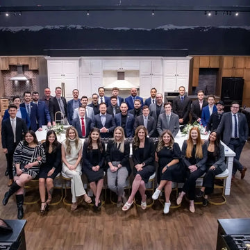 ZLINE team members in professional attire posing in a modern kitchen showroom.