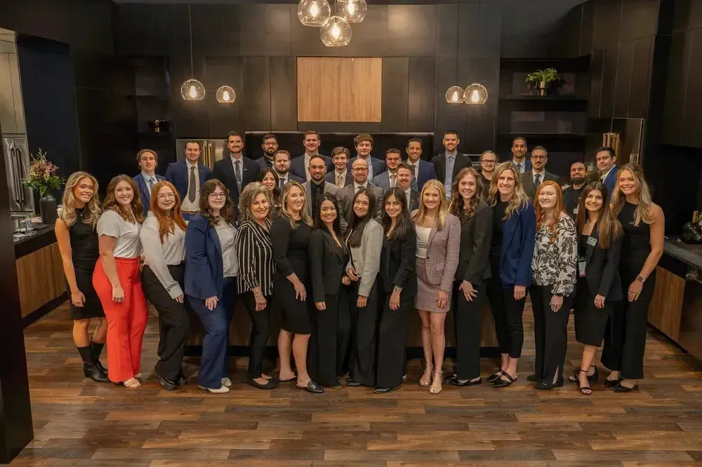 The ZLINE team posing in a modern black kitchen showroom at the 2024 KBIS trade show.
