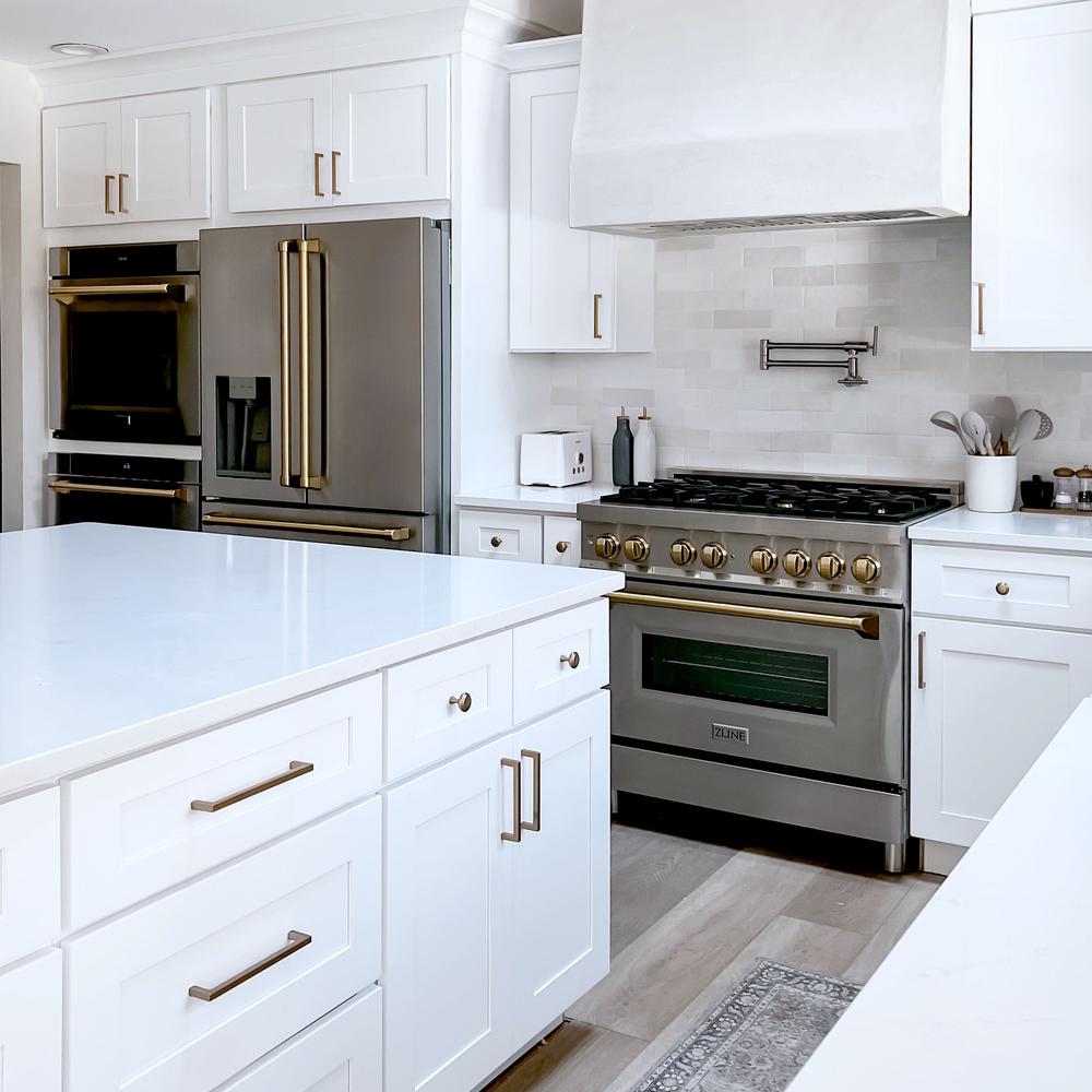 Farmhouse kitchen with white cabinets, ZLINE Autograph Edition 36 in. 4.6 cu. ft. Legacy Dual Fuel Range with 6 Burner Gas Cooktop and Electric Convection Oven in Stainless Steel and Champagne Bronze Accents (RAZ-36-CB), and marble countertops.