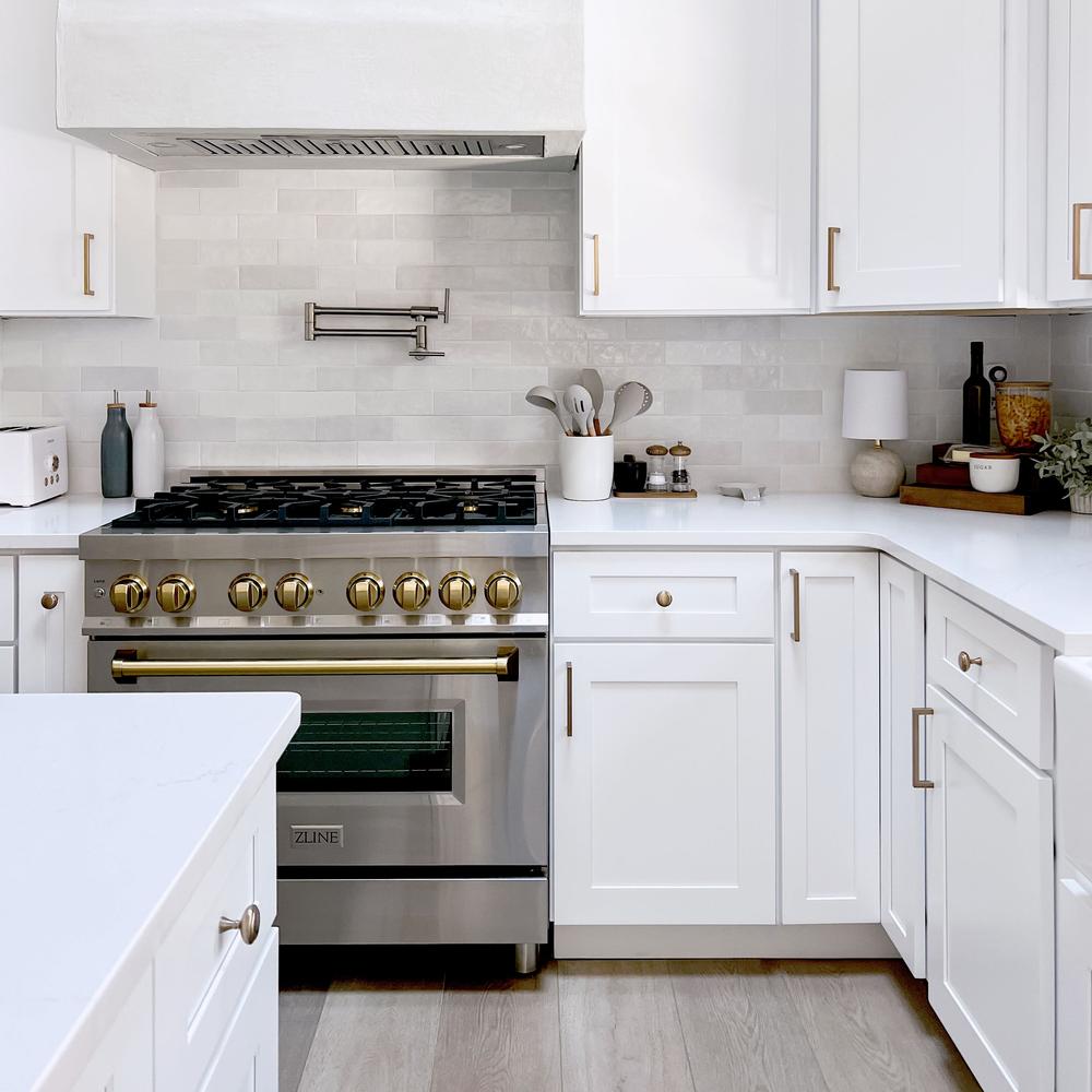 Farmhouse kitchen with white cabinets, ZLINE Autograph Edition 36 in. 4.6 cu. ft. Legacy Dual Fuel Range with 6 Burner Gas Cooktop and Electric Convection Oven in Stainless Steel and Champagne Bronze Accents (RAZ-36-CB), and marble countertop.