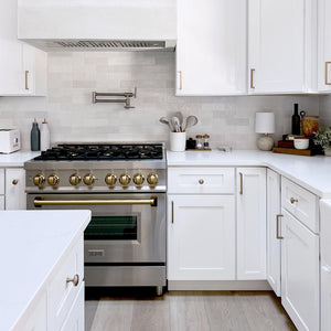 Farmhouse kitchen with white cabinets, ZLINE Autograph Edition 36 in. 4.6 cu. ft. Legacy Dual Fuel Range with 6 Burner Gas Cooktop and Electric Convection Oven in Stainless Steel and Champagne Bronze Accents (RAZ-36-CB), and marble countertop.