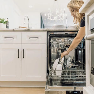ZLINE 24 in. Top Control Dishwasher with Stainless Steel Panel and Modern Style Handle, 52dBa (DW-304-24) woman loading dishes onto bottom rack.