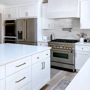 Farmhouse kitchen with ZLINE Autograph Edition 36 in. 21.6 cu. ft. Counter-Depth French Door Refrigerator with Water and Ice Dispenser in Fingerprint-Resistant Stainless Steel with Champagne Bronze Traditional Handles (RFMZ-W-36-CB), white cabinets, stainless steel appliances, and marble countertops.