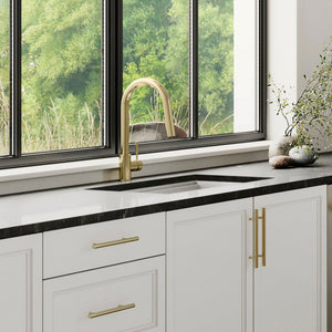 ZLINE Gemini Pull Down Single Handle Kitchen Faucet in Champagne Bronze (GEM-KF-CB) in a kitchen with white cabinets, stainless steel appliances, and black countertops.