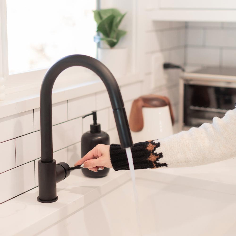 ZLINE Gemini Pull Down Kitchen Faucet in Matte Black (GEM-KF-MB) close-up, a woman turns the faucet on.