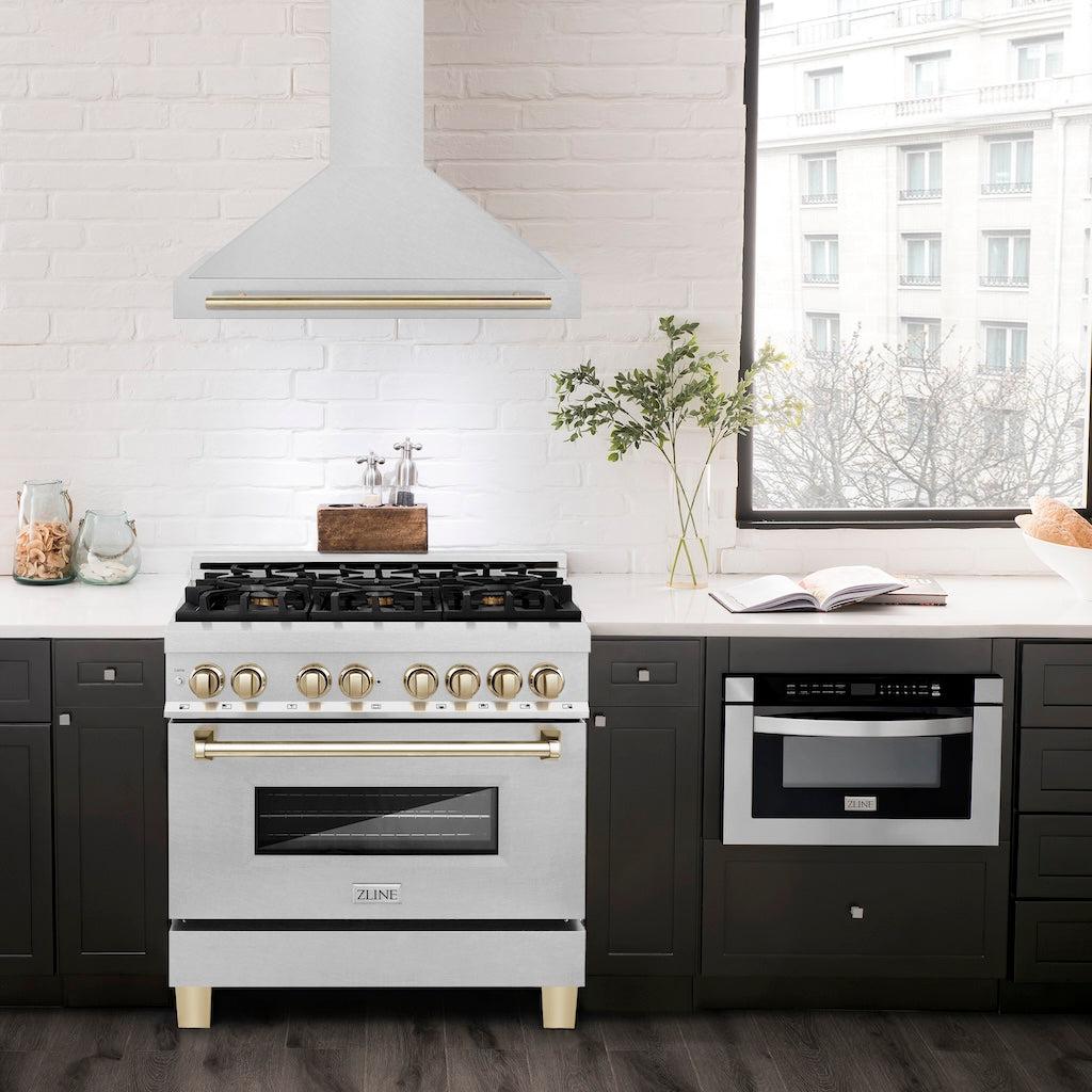 ZLINE Autograph Edition Convertible Fingerprint Resistant DuraSnow® Stainless Steel Range Hood with Polished Gold Handle (KB4SNZ-G) in a luxury compact kitchen with matching range and microwave, front.