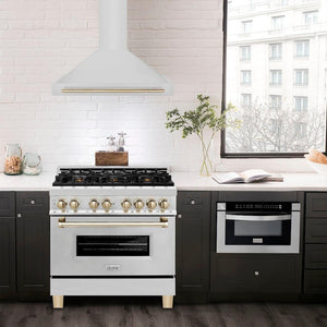 ZLINE Autograph Edition Convertible Stainless Steel Range Hood with Stainless Steel Shell and Polished Gold Accents (KB4STZ-G) in a luxury compact kitchen with matching range and microwave, front.