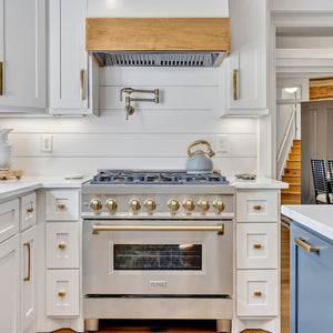 ZLINE Autograph Edition 36 in. 4.6 cu. ft. Legacy Dual Fuel Range with 6 Burner Gas Cooktop and Electric Convection Oven in Stainless Steel and Champagne Bronze Accents (RAZ-36-CB) in a rustic kitchen, front.