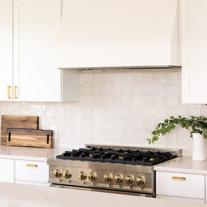 Farmhouse kitchen with a ZLINE Autograph Edition 36 in. 4.6 cu. ft. Legacy Dual Fuel Range with 6 Burner Gas Cooktop and Electric Convection Oven in Stainless Steel and Polished Gold Accents (RAZ-36-G) against a white tiled backsplash.