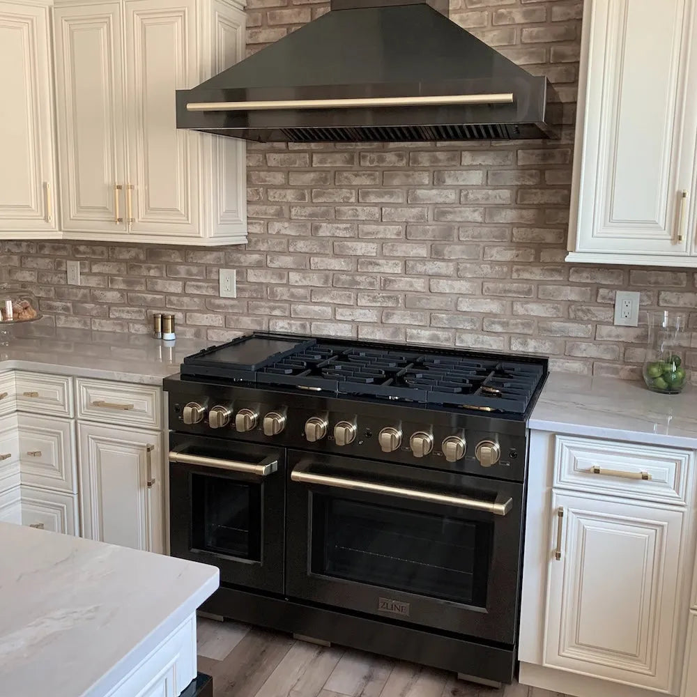 ZLINE Autograph Edition 48 in. 6.7 cu. ft. Paramount Double Oven Gas Range with 8 Burner Cooktop in Black Stainless Steel and Champagne Bronze Accents (SGRBZ-48-CB) in a kitchen with white cabinets and brick backsplash