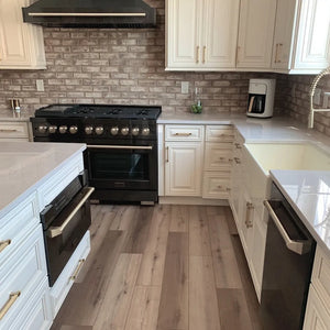 Rustic kitchen with ZLINE Autograph Edition 48 in. 6.7 cu. ft. Paramount Double Oven Gas Range with 8 Burner Cooktop in Black Stainless Steel and Champagne Bronze Accents (SGRBZ-48-CB), black appliances, white cabinets, and wooden flooring.