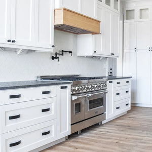 Farmhouse kitchen with white cabinets, stainless steel appliances, wooden flooring, and a custom range hood using a ZLINE 46 in. Ducted Wall Mount Range Hood Insert in Stainless Steel (695-46).
