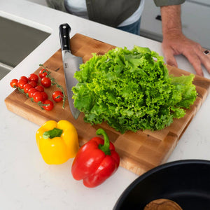 ZLINE 8 in. Professional German Steel Chef’s Knife (KCKT-GS) on a cutting board with fresh lettuce and cherry tomatoes, side.