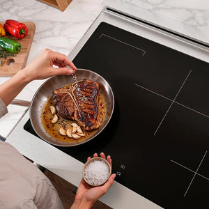 Person seasoning a steak in a pan on a ZLINE 30 in. Paramount Induction Rangetop with 4 Element Cooktop in Stainless Steel (SINRT30)