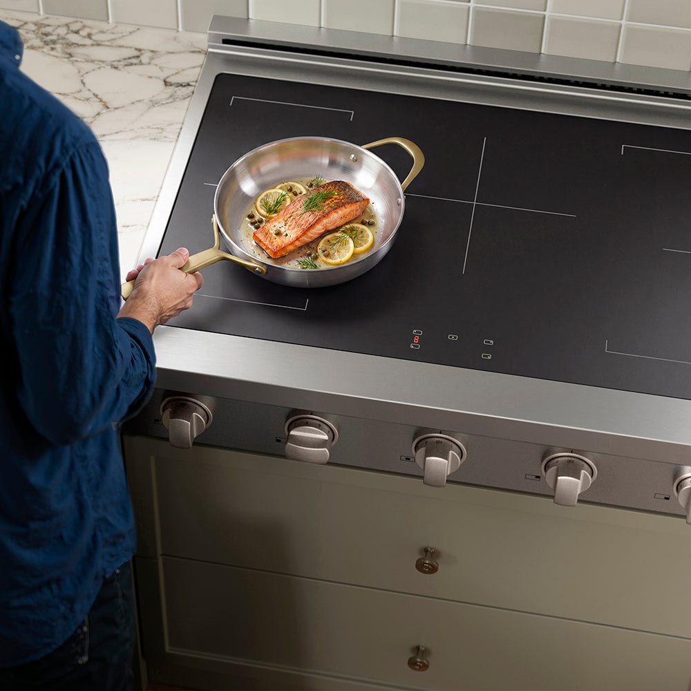 Person cooking salmon with lemon slices on a ZLINE 36 in. Paramount Induction Rangetop with 5 Element Cooktop in Stainless Steel (SINRT36)