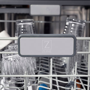 ZLINE Autograph Edition 24 in. Monument Series 3rd Rack Top Touch Control Tall Tub Dishwasher in Black Stainless Steel with Polished Gold Helix Handle, 45dBa (DWMTZ-BS-24-KG) logo on dish rack with dishes in the background.