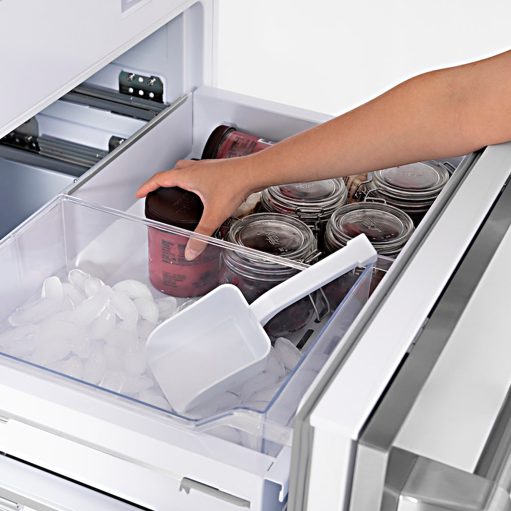 ZLINE Autograph Edition 60 in. 32.2 cu. ft. Panel Ready French Door Built-In Bottom Freezer Refrigerator with Water Dispenser and Ice Maker with Champagne Bronze Accents (RBIVZ-60-CB) hand reaching into freezer drawer filled with containers and ice cubes.