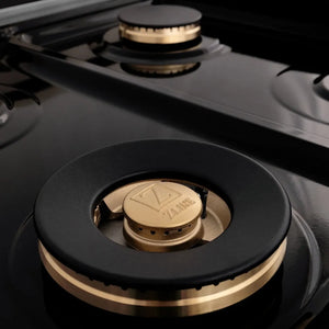 ZLINE Autograph Edition 60 in. 7.4 cu. ft. Legacy Dual Fuel Range with 9 Burner Gas Cooktop and 2 Electric Convection Ovens in Satin Stainless Steel with White Matte Doors and Champagne Bronze Accents (RASZ-WM-60-CB) detail, large brass burner on black porcelain cooktop.