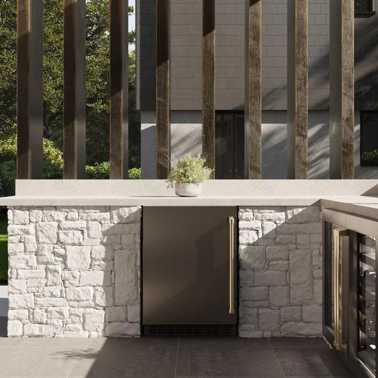 ZLINE Autograph Edition 24 in. Touchstone 151 Can Beverage Fridge With Solid Stainless Steel Door And Champagne Bronze Handle (RBSOZ-ST-24-CB) front, in a luxury outdoor kitchen.