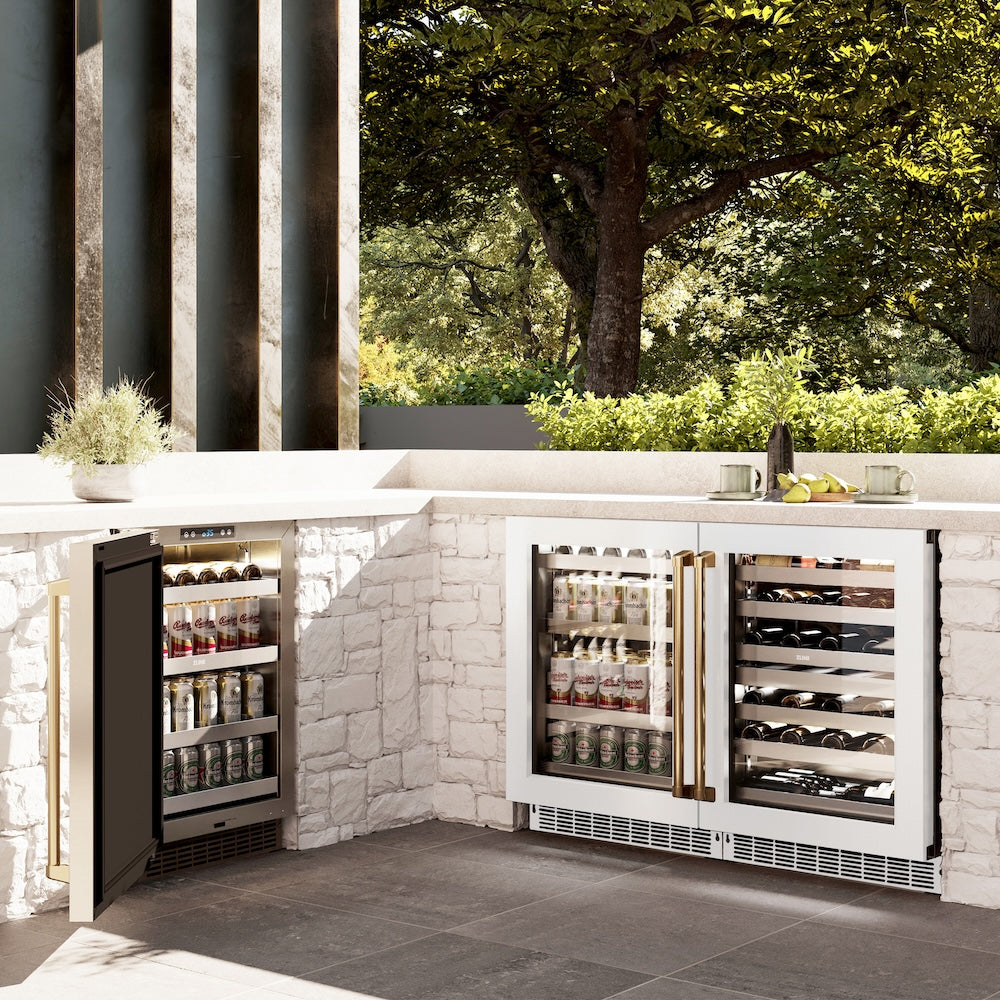 ZLINE Autograph Edition 24 in. Touchstone Dual Zone 44 Bottle Wine Cooler With White Matte Glass Door And Polished Gold Handle (RWDOZ-WM-24-G) side, in an outdoor kitchen with two matching beverage fridges displaying drinks and bottles.