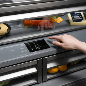 ZLINE Autograph Edition 36 in. 19.6 cu. ft. French Door Built-In Bottom Freezer Refrigerator with Water Dispenser and Ice Maker in Black Stainless Steel with Graphite Gray Interior and Champagne Bronze Helix Handles (GRBIVZ-BS36KCB) hand adjusting digital touch temperature control inside refrigeration compartment with food items.