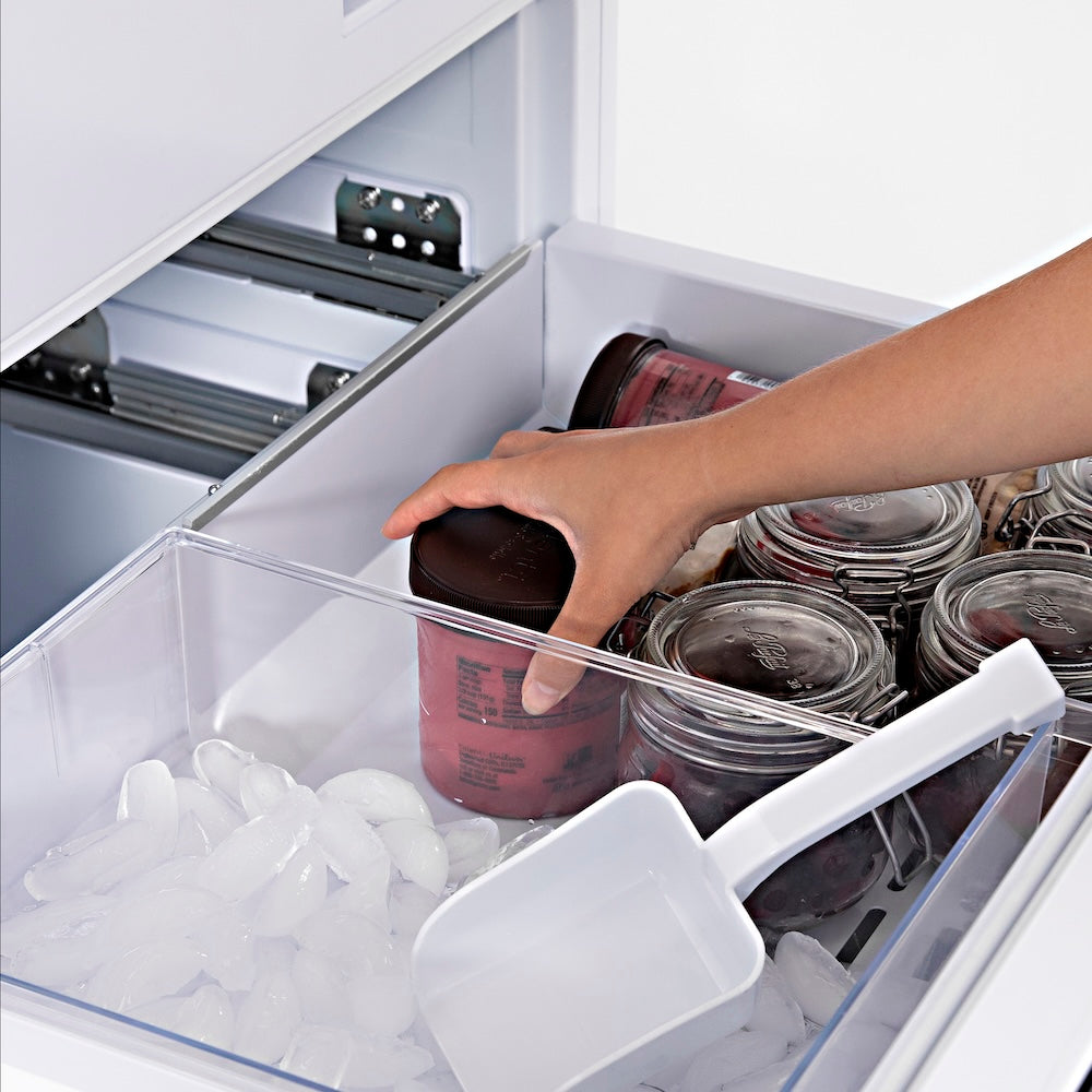 ZLINE 30 in. 16.1 cu. ft. Panel Ready Built-In Bottom Freezer Refrigerator with Water Dispenser and Ice Maker (RBIV-30) hand reaching into freezer drawer filled with containers and ice cubes.
