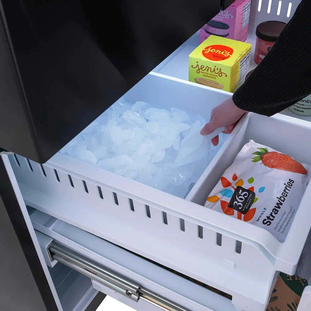 Hand reaching into ZLINE 36 in. 28.9 cu. ft. Standard-Depth French Door External Water Dispenser Refrigerator with Dual Ice Maker in Fingerprint-Resistant Black Stainless Steel (RSM-W-36-BS) bottom freezer drawer filled with ice cubes, with a focus on the ice cube tray.