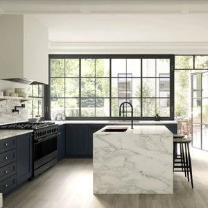 ZLINE 48 in. 6.7 cu. ft. Marino Double Oven Gas Range with 8 Burner Cooktop in Black Stainless Steel (MGRB-48) side, in a modern kitchen interior with dark navy cabinetry, a white marble island, black faucets, and large black-framed windows overlooking greenery.