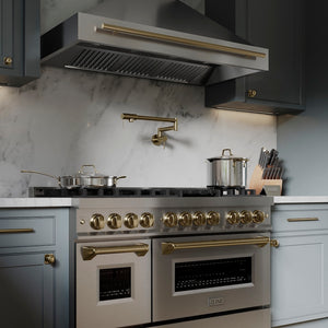 Modern kitchen with ZLINE Autograph Edition 48 in. 6.0 cu. ft. Legacy Dual Fuel Range with 7 Burner Gas Cooktop and 2 Electric Ovens in Stainless Steel and Champagne Bronze Accents (RAZ-48-CB) and range hood against a marble backsplash.