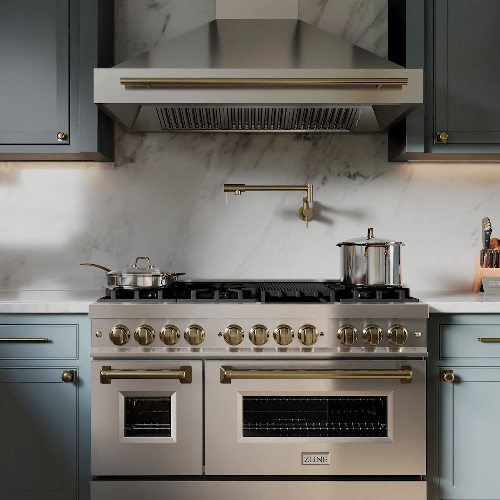ZLINE Gemini Pot Filler in Champagne Bronze (GEM-FPF-CB) in a kitchen with a range and range hood against a marble backsplash.