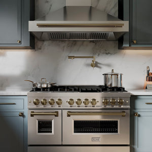ZLINE Gemini Pot Filler in Champagne Bronze (GEM-FPF-CB) in a kitchen with a range and range hood against a marble backsplash.