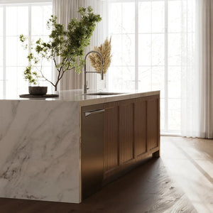 ZLINE 24 in. Monument Series 3rd Rack Dishwasher with Auto Door Open Drying, 44dBa, Stainless Steel Panel (DWMT-304-24) in a kitchen island with marble countertop and wooden cabinets, featuring a plant and decorative items.