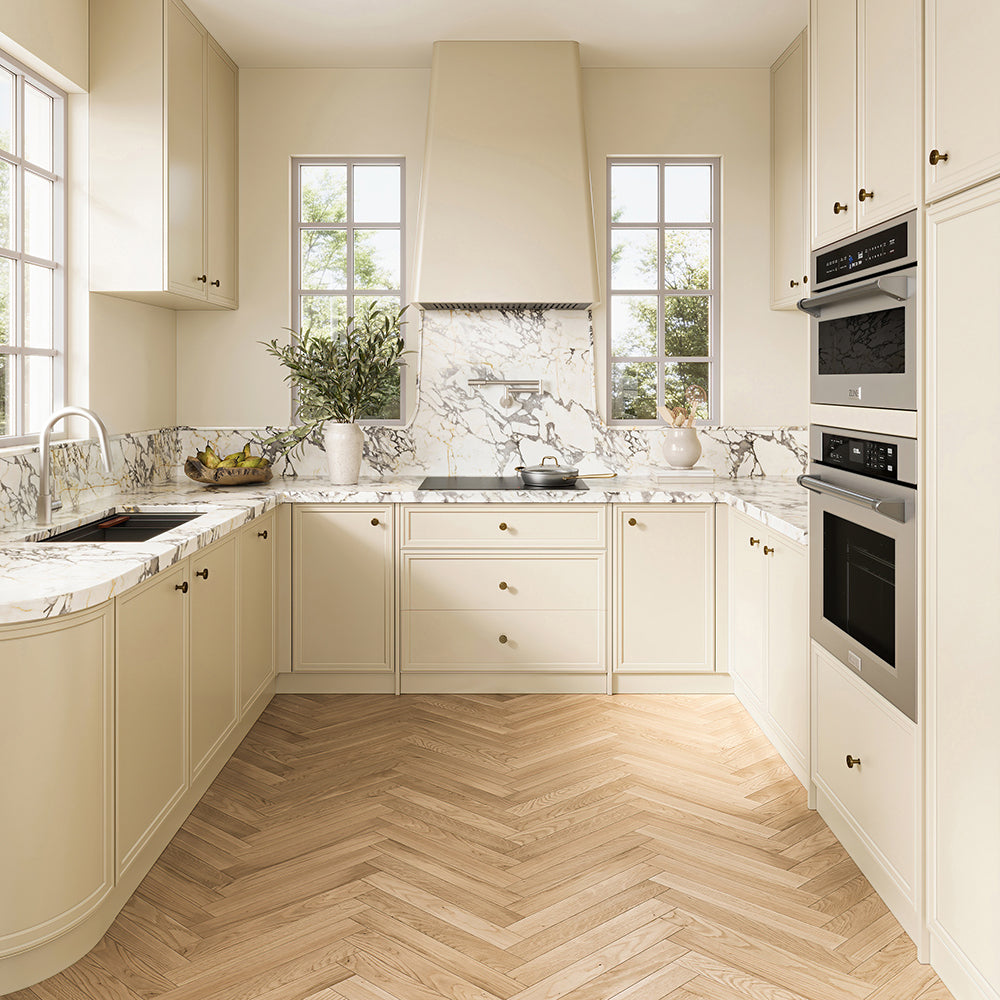 ZLINE 30 in. Induction Cooktop with Anti-Scratch Glass and 4 Elements (FCIND-30) in a modern U-shaped kitchen featuring cream-colored cabinets, white marble countertops and backsplash, light wood herringbone flooring, and stainless steel built-in appliances.