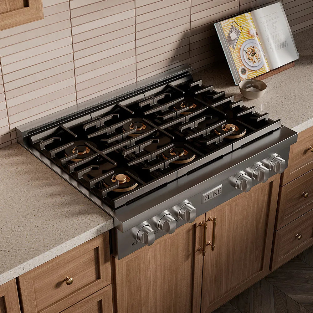 ZLINE 36 in. Paramount Gas Rangetop with 6 Burner DuoPro™ Cooktop in Stainless Steel (PSRT36) in a kitchen setting with wooden cabinets and a cookbook.