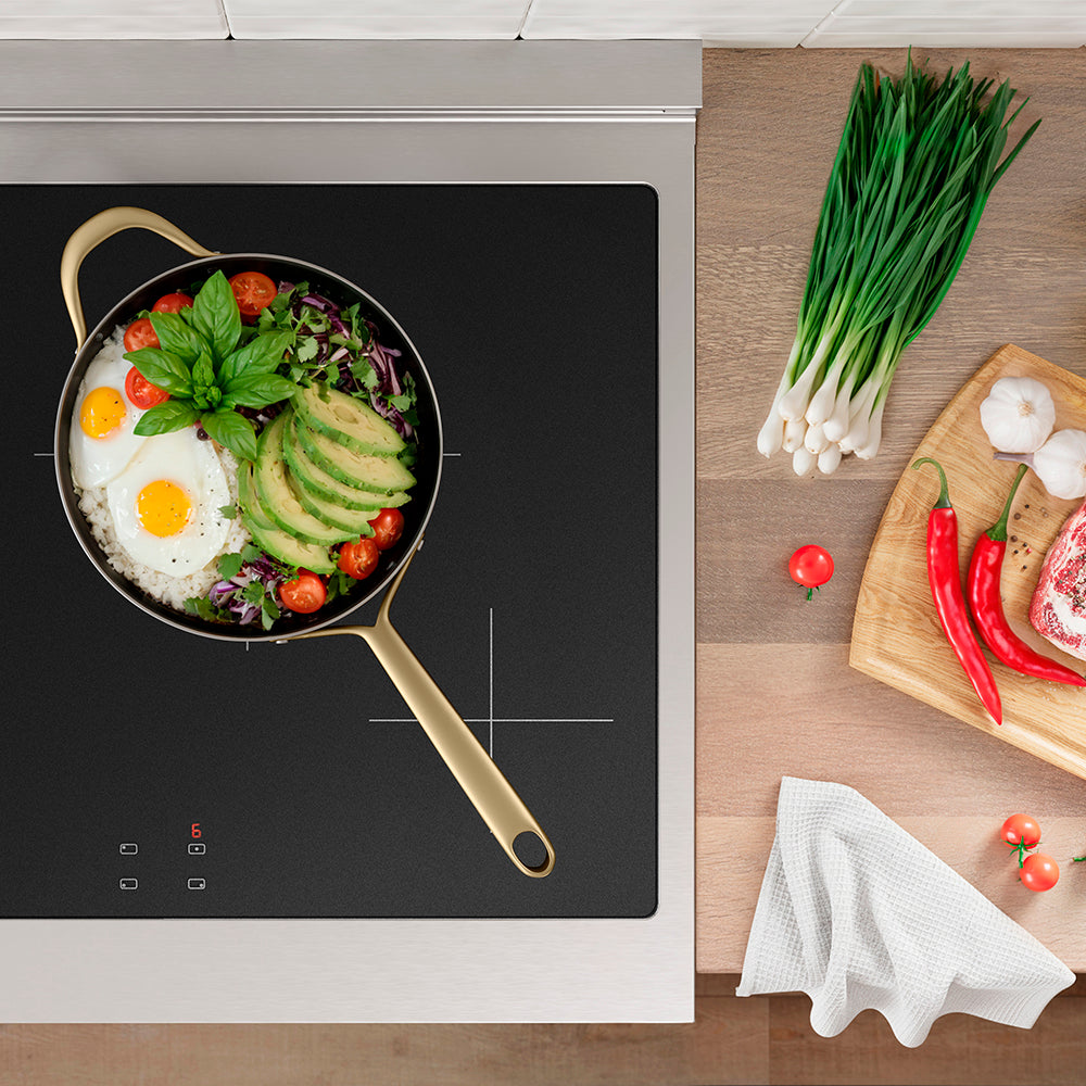 ZLINE Autograph Edition 30 in. 4.2 cu. ft. Paramount Induction Range with 4 Element Cooktop and Electric Convection Oven in Stainless Steel with White Matte Door and Polished Gold Accents (SINRZ-WM-30-G) top-down, induction cooktop with a pan of food and ingredients on a wooden countertop